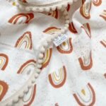 "Rausvos vaivorykštės" muslino pledukas su mini pom poms